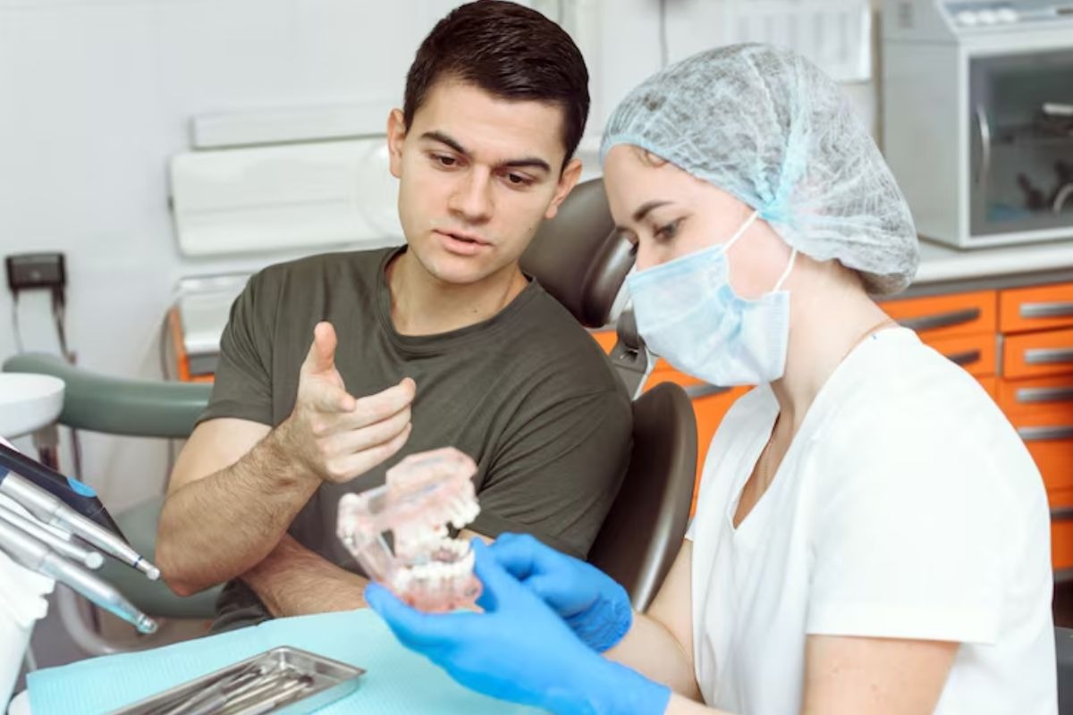 young patient discussing a root canal with a dentist using a tooth model.